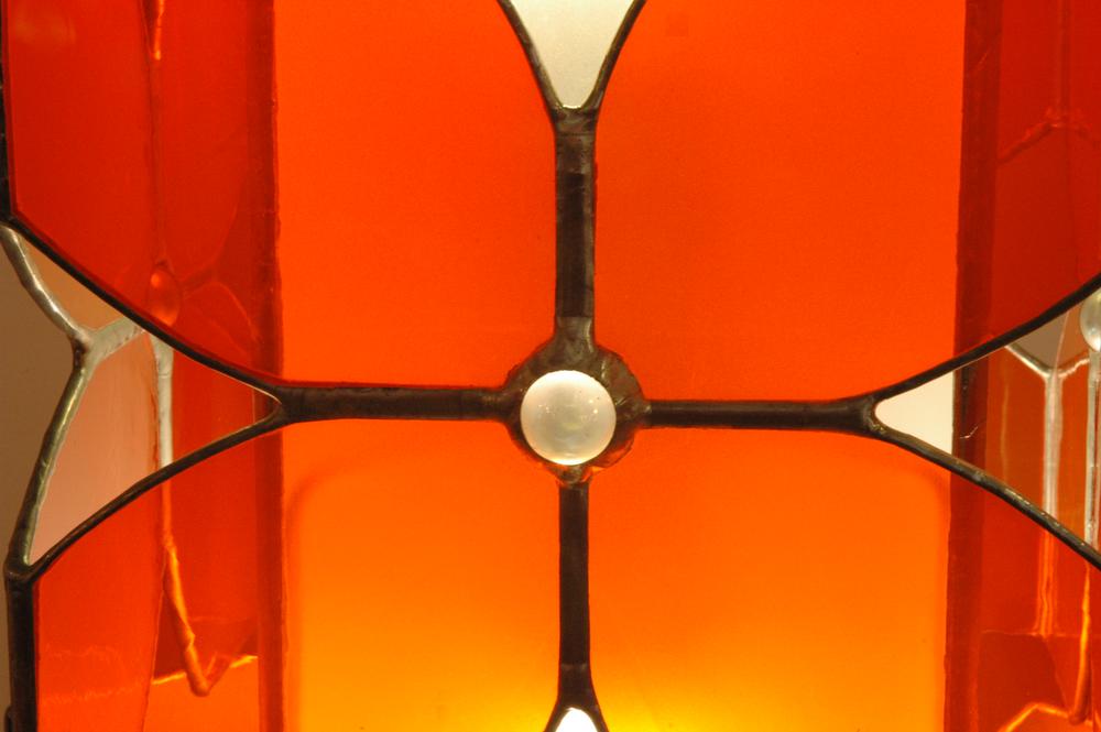 Vitraux oranges et noirs pour cette lampe à poser. Equipée de deux ampoules elle constitue une source de lumière intéressante en lampe d'appoint intégrée à la déco, sur un bureau ou une table de chevet.